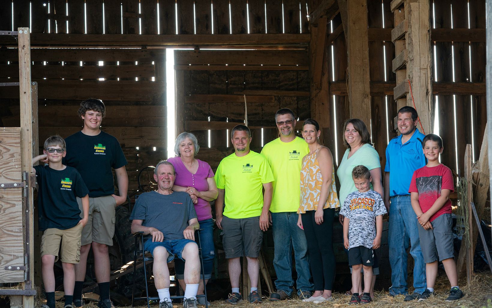 Eleven members of the Guilette family stand and pose inside a barn at their family farm.