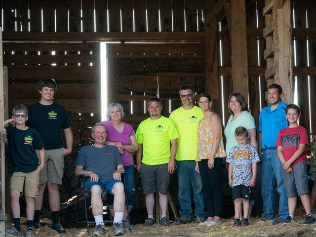 Eleven members of the Guilette family stand and pose inside a barn at their family farm.