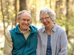A smiling couple in a sunny wooded setting