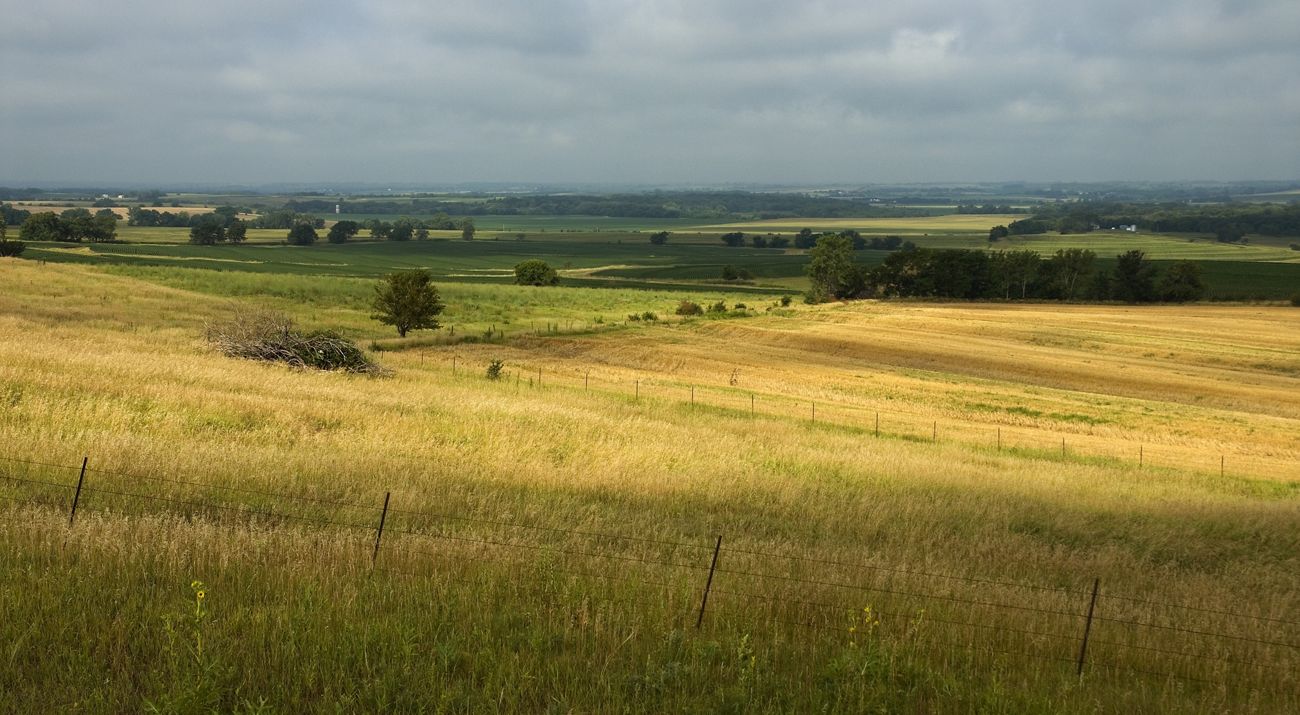 Sweeping view of farmlands in Nebraska under cloudy sky.