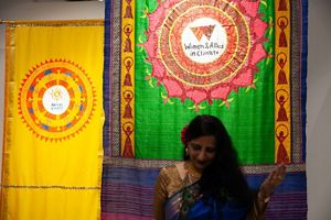 Neha Misra with her head bowed in front of the sari she painted for Women & Allies in Climate.