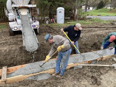 Workers pour and level cement in a housing construction area.