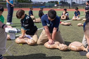Children practice chest compressions on manikins while learning CPR on the field as part of the NFL's PLAY 60 health and wellness initiative.