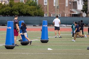 A young girl and a young boy run across the field towards bright blue tackling equipment as part of the NFL's PLAY 60 health and wellness initiative.