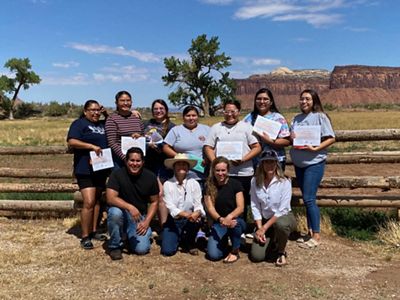 Several people stand together in front of a wooden fence and pose for the camera.