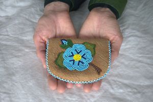 Two hands hold out a small beaded purse.