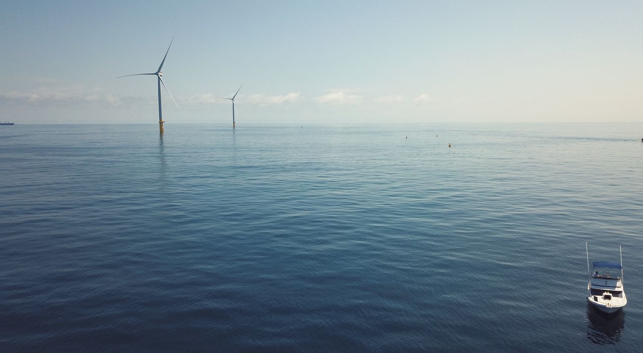 A aerial view of an ocean with wind turbines.