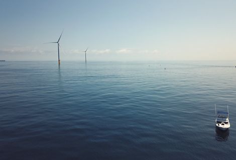 An aerial view of ocean with wind turbines.