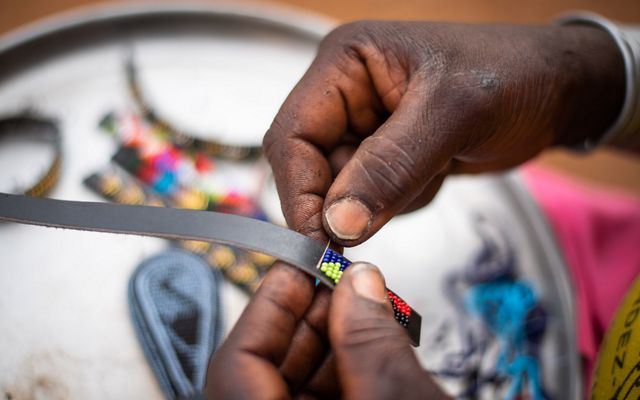 Joyce Lelukai crafts a beaded strap for Beadworks at her home (boma) in Kalama Conservancy.  