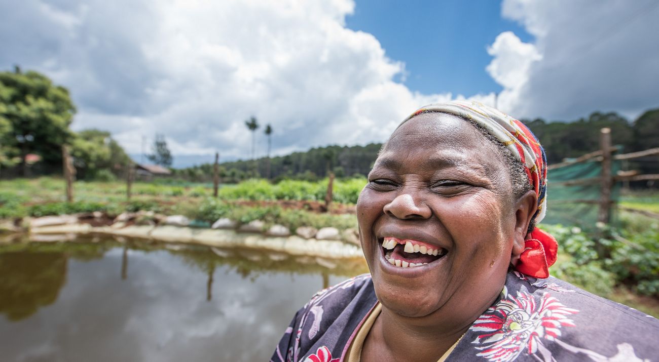 Elena Kinyua stands in front of a rainwater harvesting water pan she built with support from the Upper Tana-Nairobi Water Fund