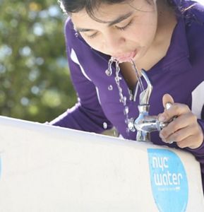 Close up of person drinking from a water fountain.