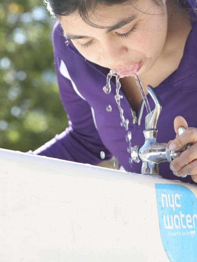 Close up of person drinking from a water fountain.
