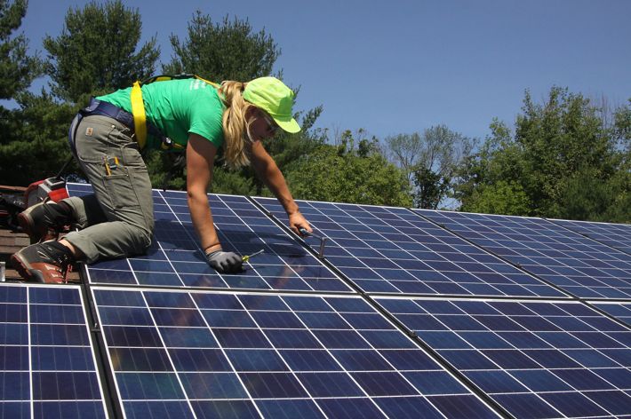A women installing solar panels on a roof.