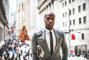 A person in a business suit stands in downtown New York City.