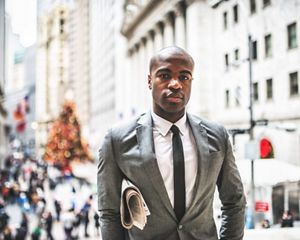 A person in a business suit stands in downtown New York City.