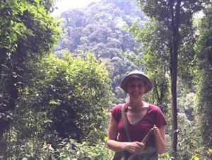 A woman smiling in a heavily forested area.
