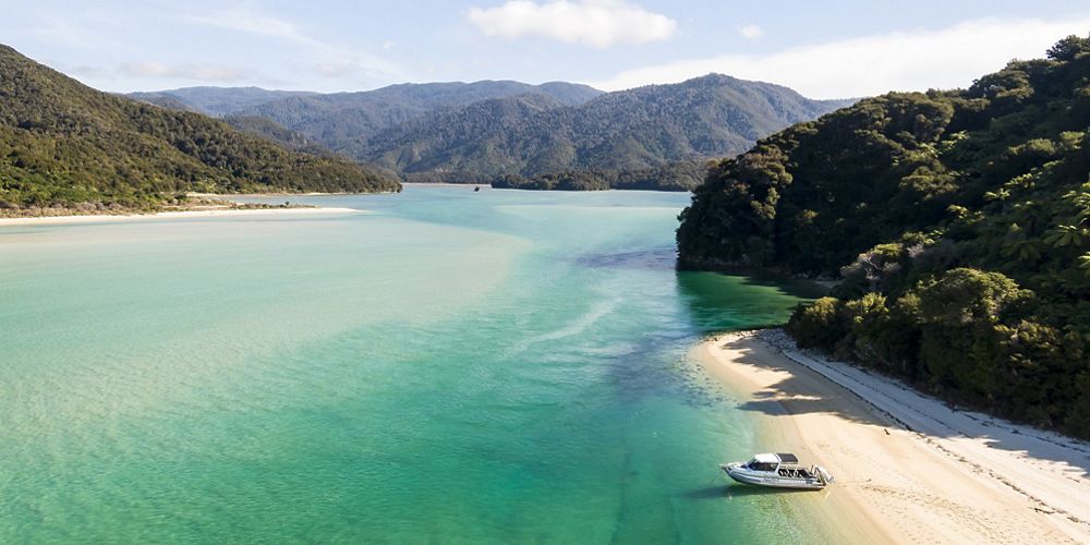 View overlooking a wide, flat body of water, with a small beach abutting forested hills.
