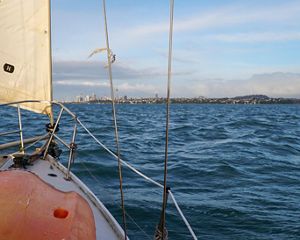 View of bay from aboard sailboat with city skyline in background.
