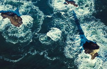 Aerial view of water moving around rock formations at La Push Beach in Washington.