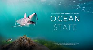 This is a movie poster with a large shark swimming toward the foreground with the words Ocean State in white text to the right of the shark against a teal blue backdrop.