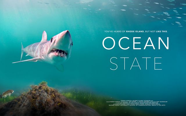 This is a movie poster with a large shark swimming toward the foreground with the words Ocean State in white text to the right of the shark against a teal blue backdrop.