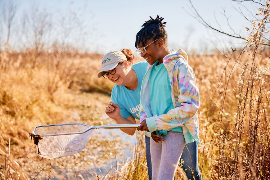 child learning in nature with educator.