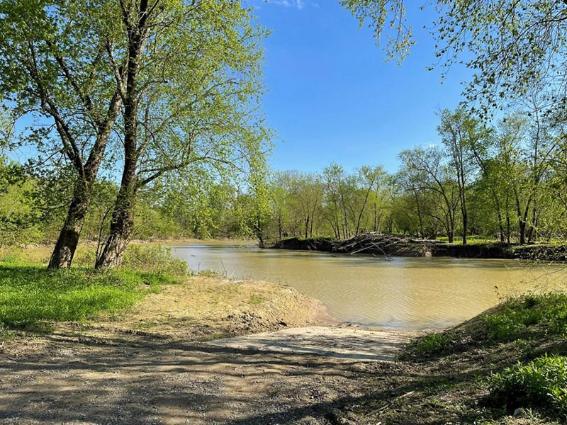 A dirt boat ramp leads to a river in a forested area of Mackenzie Run.