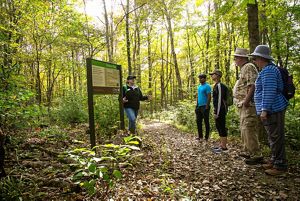 A TNC staffer introduces a group of hikers to a trail in a forest.