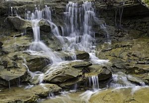 A small waterfall flows on grey rocks.