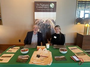 Two people sitting at a booth with merch.