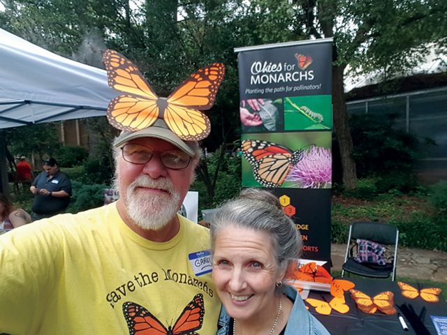 Two people standing together with monarch butterflies.
