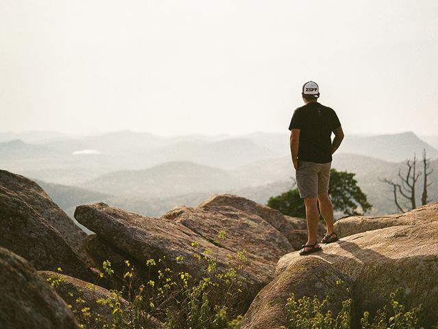 Man standing on mountain rocks overlooking the valley.