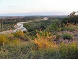 A landscape view of a river flowing through grasslands.