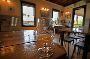 A small rounded glass with beer sits on a table.
