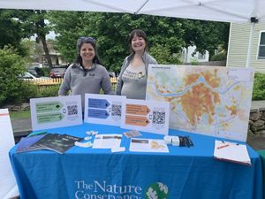 Two TNC staff members at a table with posters at a festival.