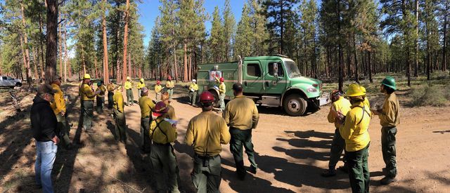 Photo of a multi-agency team standing in circle, preparing for a controlled burn in Oregon.