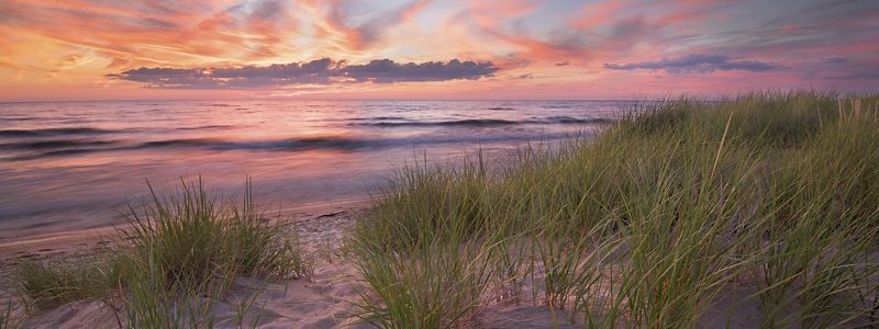 The sun sets over Oval Beach and reflects in the water.