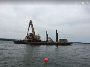 A large barge with a crane in the middle of the water.