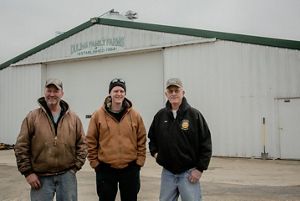 Jeff Duling poses with his son and his father outside a farm building.