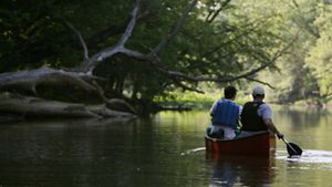 Two men canoe in a river.