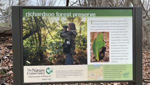 In image of a sign shares about The Nature Conservancy's role in protecting a nature preserve.