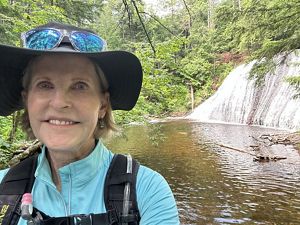 Nancy Gotfredson smiling with a waterfall in the background.