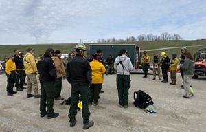 People stand in a circle in front of a trailer with a map.