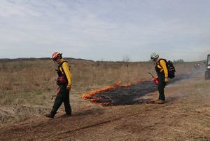 Two women in fire hear smile with a line of fire in the background.