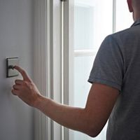 An adult with their finger on a light switch.