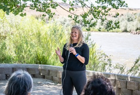 A woman speaking into a microphone to an audience.