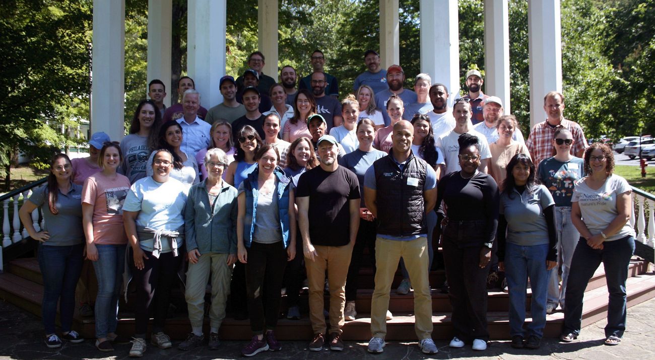 Group photo of TNC MD/DC staff. A large group of people stand together outdoors in a gazebo, smiling during the chapter's annual staff retreat.