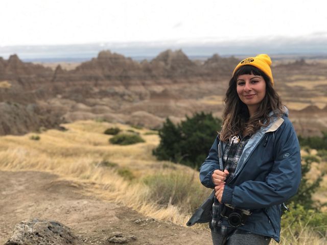 Candid photo of Development Program Associate Melisa Soysal in an open plateau with sandstone formations lining the horizon.