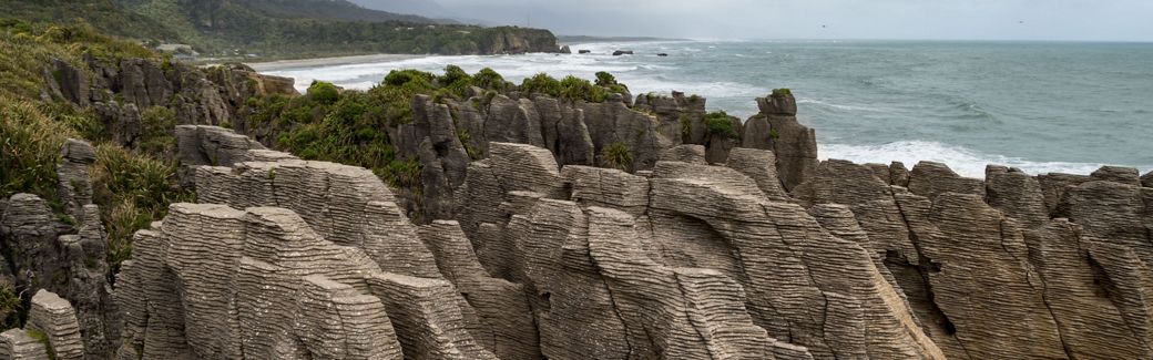 A rocky shoreline made up of thousands of layers of rock in the foreground with the ocean in the background.