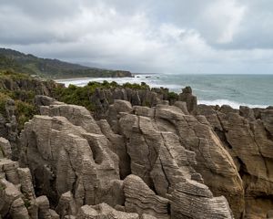 A rocky shoreline made up of thousands of layers of rock in the foreground with the ocean in the background.
